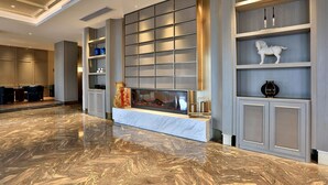 A spacious lobby with a marble floor, a fireplace, and modern shelving units. - Byland Star Hotel (Jinhua)