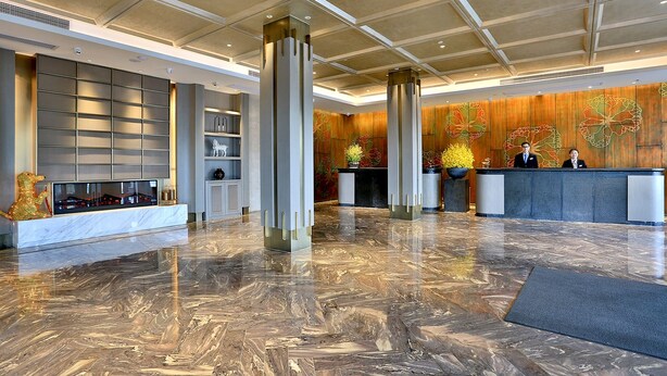 A spacious lobby with a marble floor, a reception desk, and a large wall with a floral mural. - Byland Star Hotel (Jinhua)