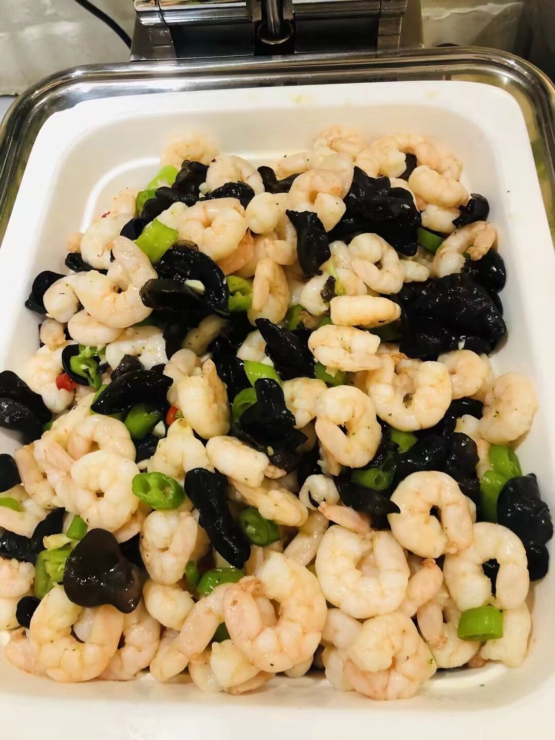 A dish of cooked shrimp with black olives and green peppers.
