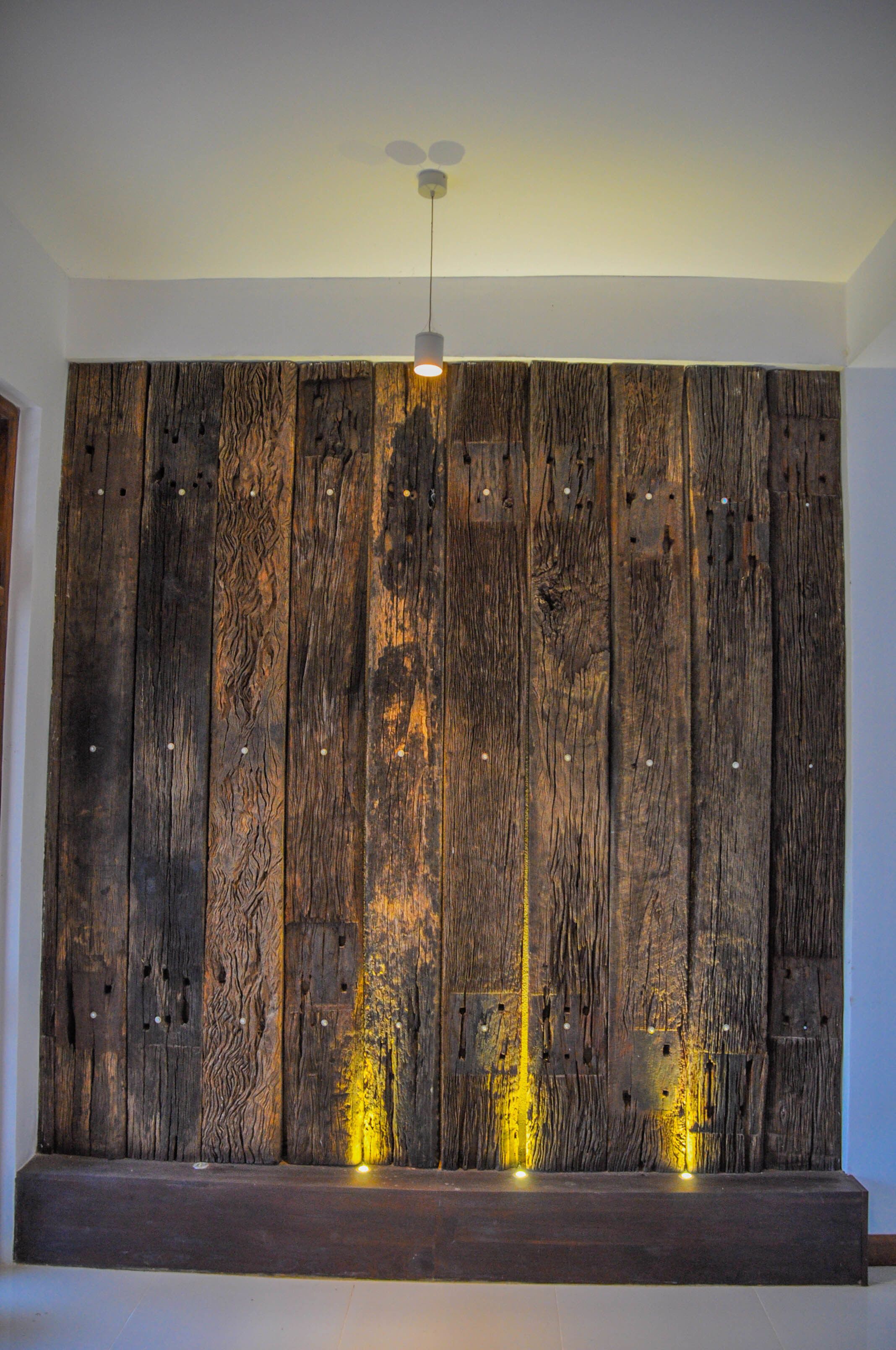 Pared con textura de madera rústica y una lámpara moderna en el techo.