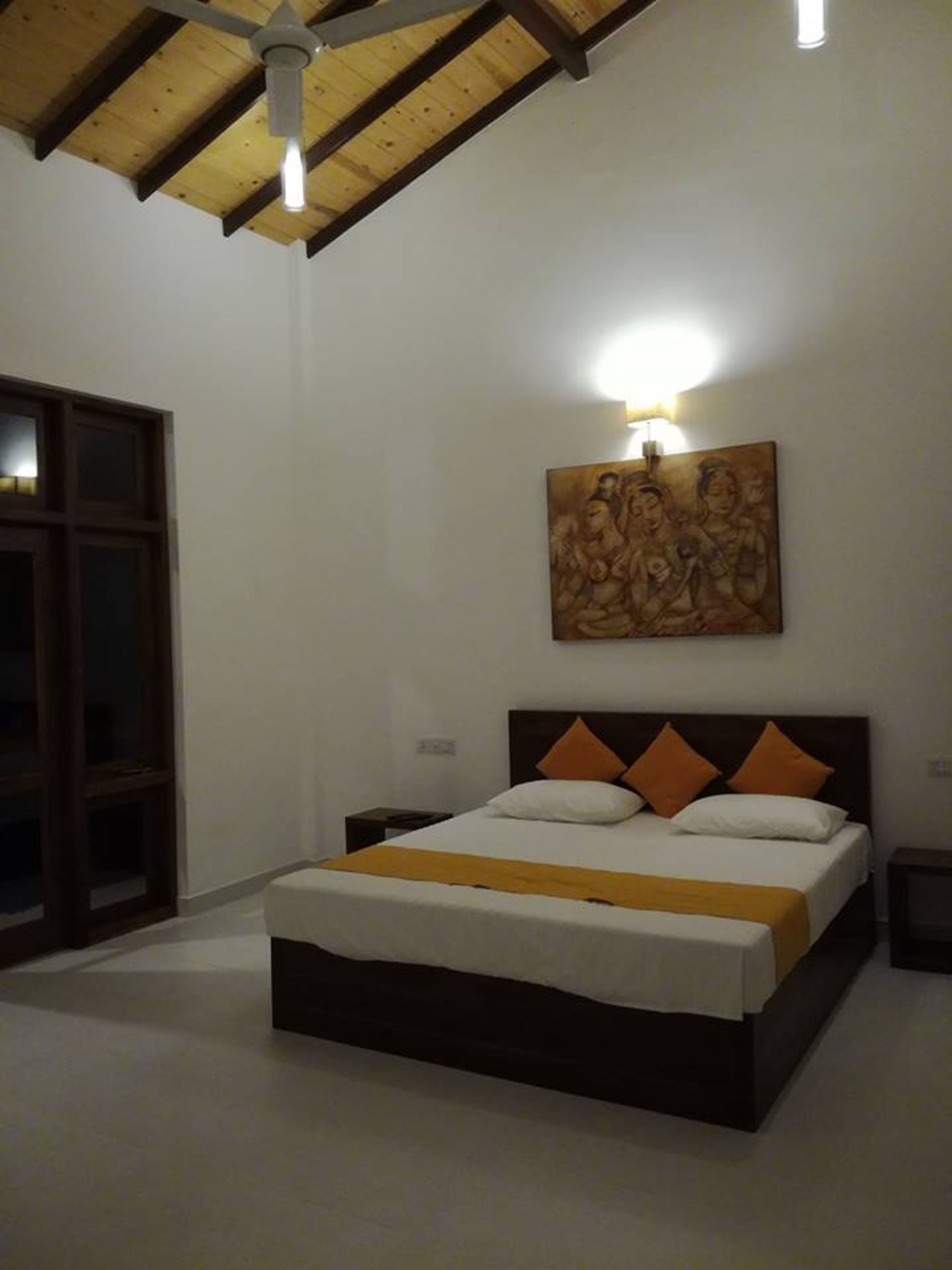 A bedroom with a bed, a nightstand, a wall-mounted light, and a ceiling fan.