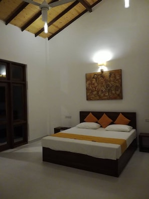 A bedroom with a bed, a nightstand, a wall-mounted light, and a ceiling fan.