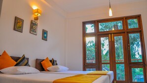 Habitación de hotel con dos camas, un ventanal con vistas a la vegetación e iluminación empotrada en la pared.