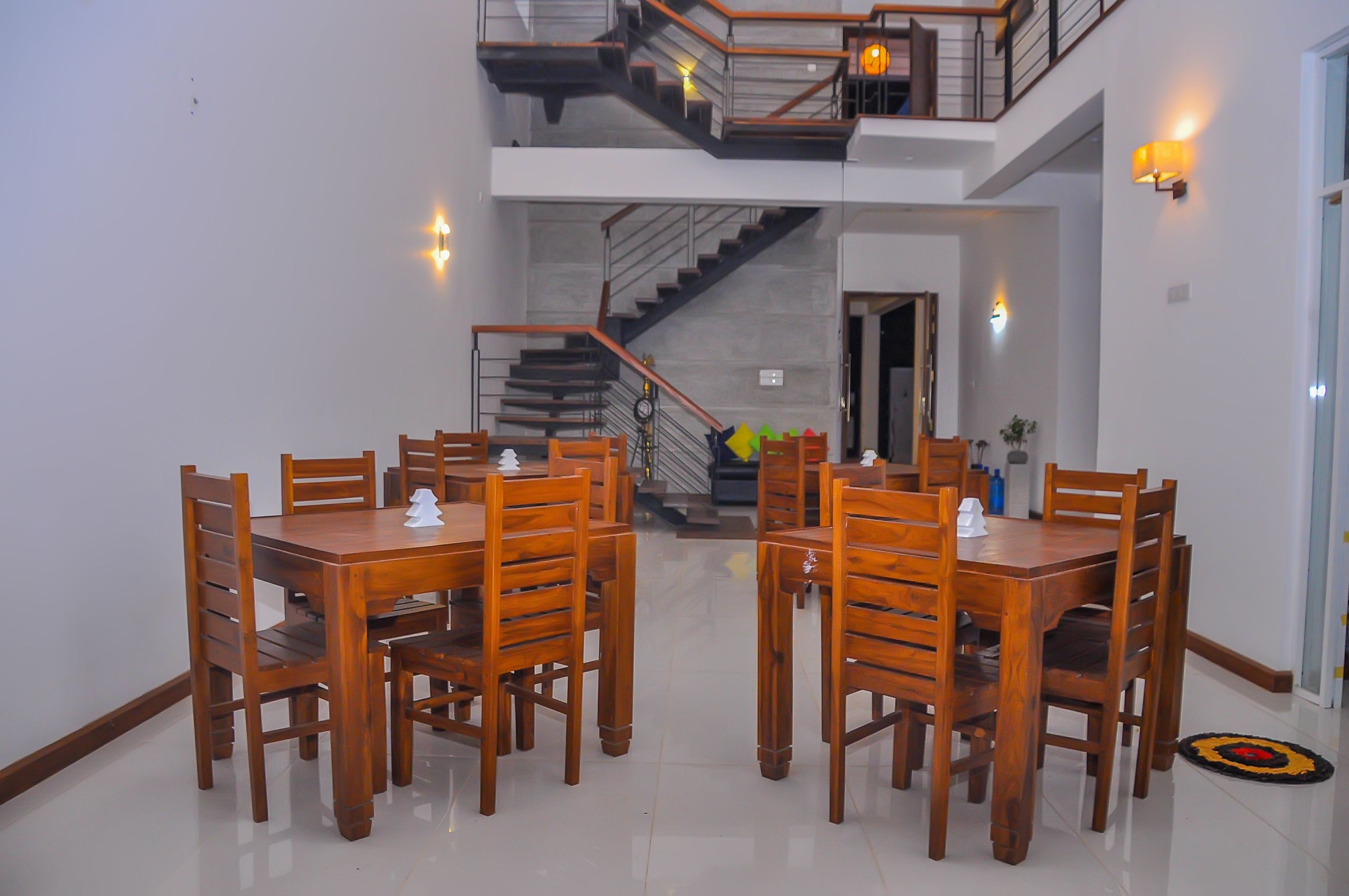 Un espace repas avec des tables et des chaises en bois, un escalier et une vue sur l’étage supérieur.