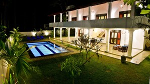 A two-story building with a swimming pool, outdoor seating, and a well-maintained garden. - Silence Garden (Hikkaduwa)