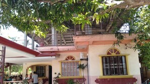 Un bâtiment à deux étages doté d’un patio couvert, de plantes en pot et d’une moto garée.