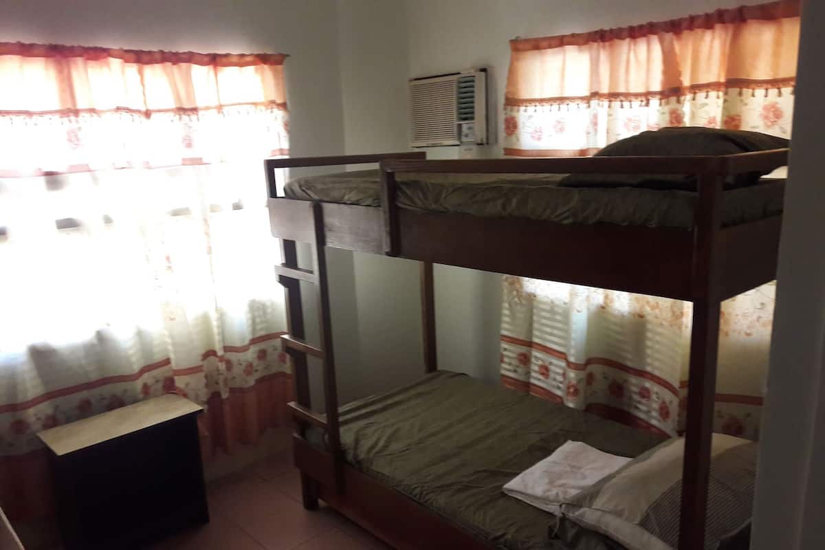 Une chambre avec un lit superposé, un petit bureau et un radiateur.