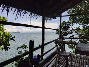 A wooden deck with a view of the sea, bamboo railings, and some greenery. - Guimaras Mangrove Guesthouse (Nueva Valencia)