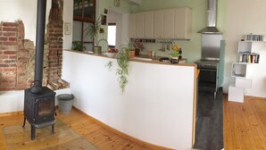 A kitchen with a brick wall, a wood-burning stove, white cabinets, and a modern oven. - ____To Bachrauschen____Wohlfuelwohnung in the picturesque Ulm valley, 5km to the Lahn valley (Greifenstein-Ulm)