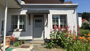 A two-story house with a white exterior, a brown roof, and a front porch. - ____To Bachrauschen____Wohlfuelwohnung in the picturesque Ulm valley, 5km to the Lahn valley (Greifenstein-Ulm)