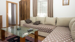 Een woonkamer met een glazen salontafel, een bank met stippelkussens, een houten garderobe en een lijst met een foto aan de muur.