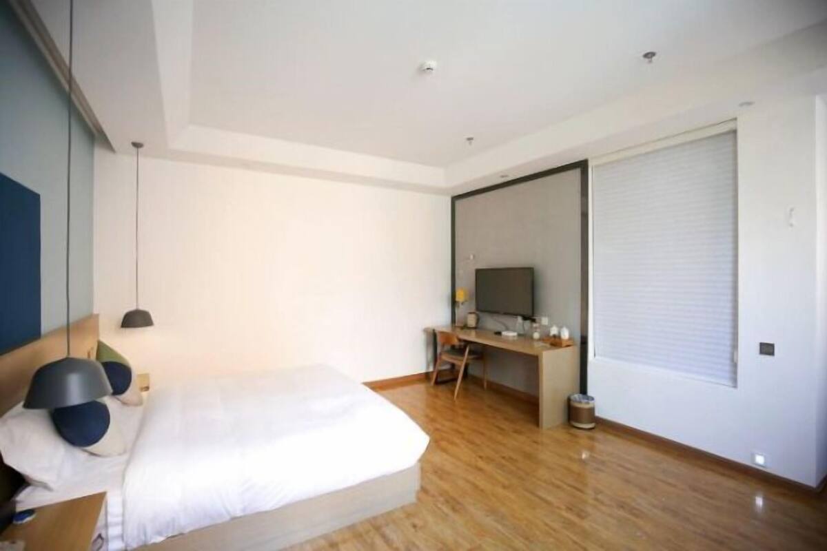 A modern bedroom with a bed, a desk, and a television.