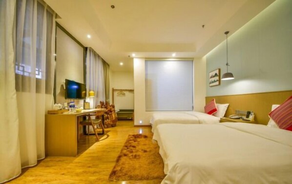 Habitación de hotel con dos camas, un escritorio con silla, televisor y ventana con cortinas.