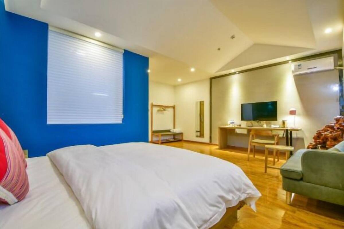 A hotel room with a bed, a desk with a computer, a TV, and a chair.