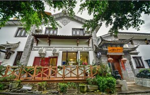 A traditional building with a balcony, potted plants, and a red door.