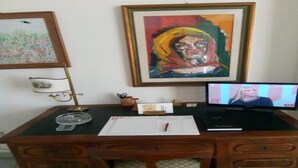 A wooden desk with a television, papers, and a lamp.