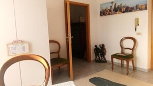 A room with a wooden chair, a table, a painting of a cityscape, and a calendar on the wall.
