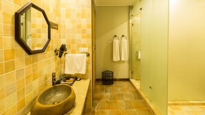 Een badkamer met een wasbak van steen, een spiegel en betegelde muren.