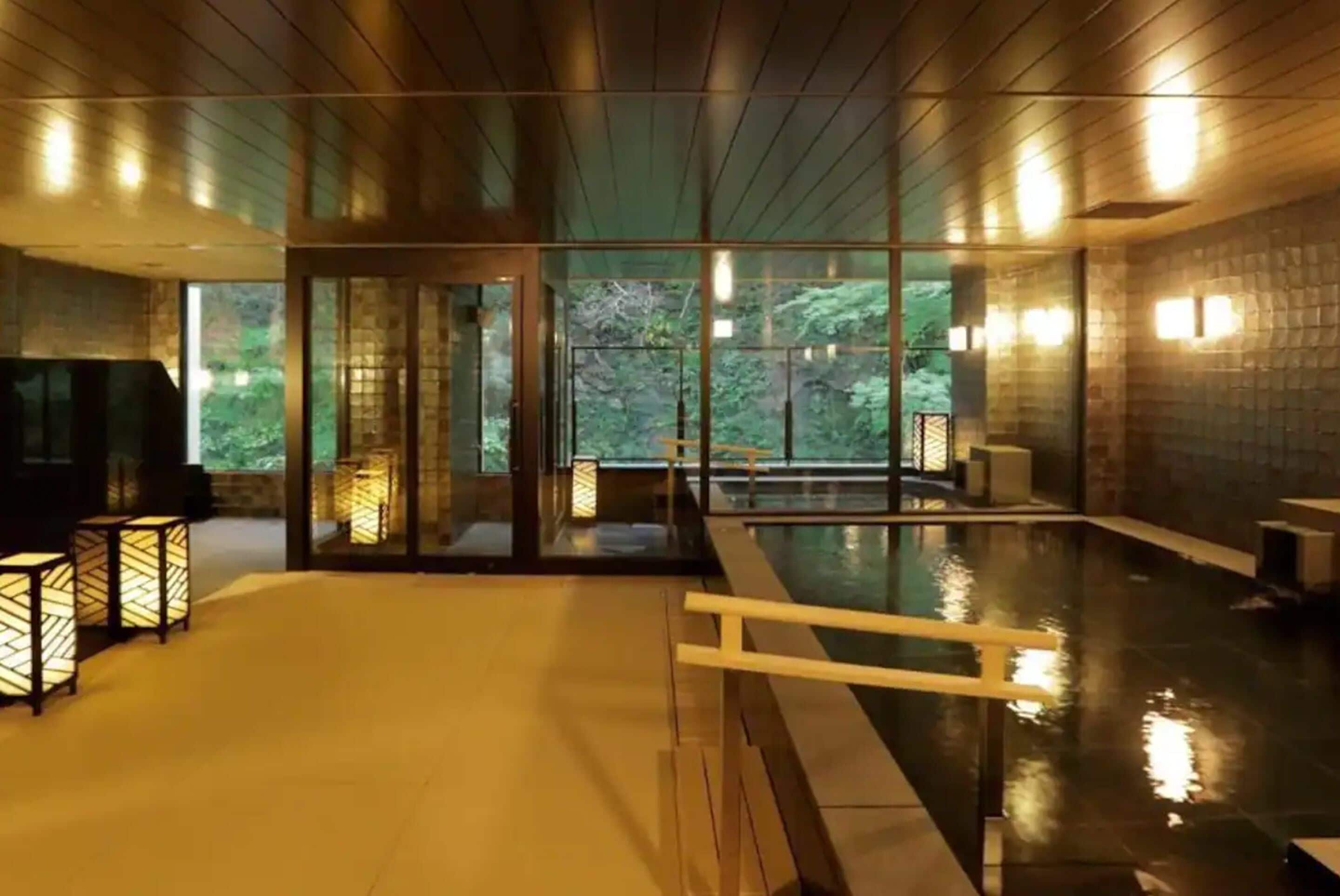 Et spa-område med træloft, glasdøre, pool og stemningsbelysning.