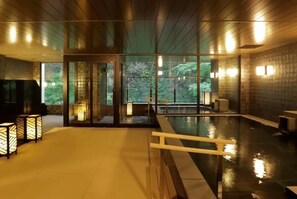 Un espace de bien-être doté d’un plafond en bois, de portes vitrées, d’une piscine et d’un éclairage d’ambiance.