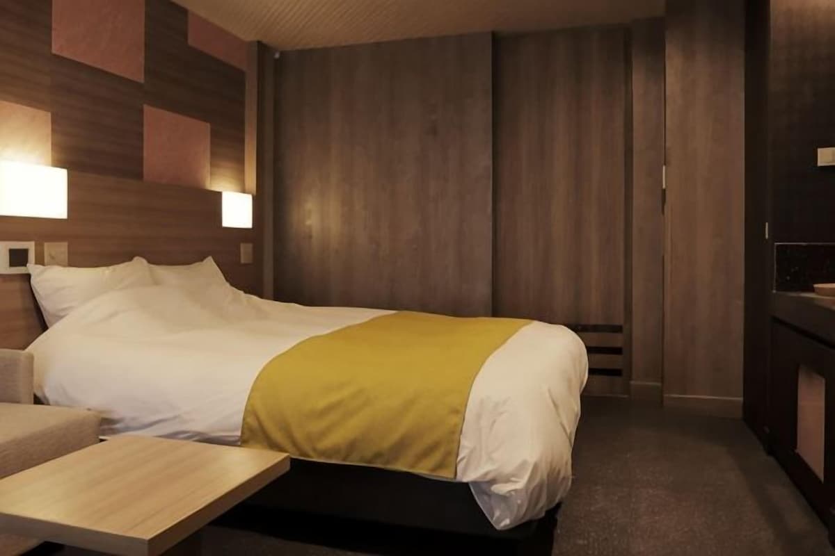 A hotel room with a bed, bedside table, and a wooden headboard.