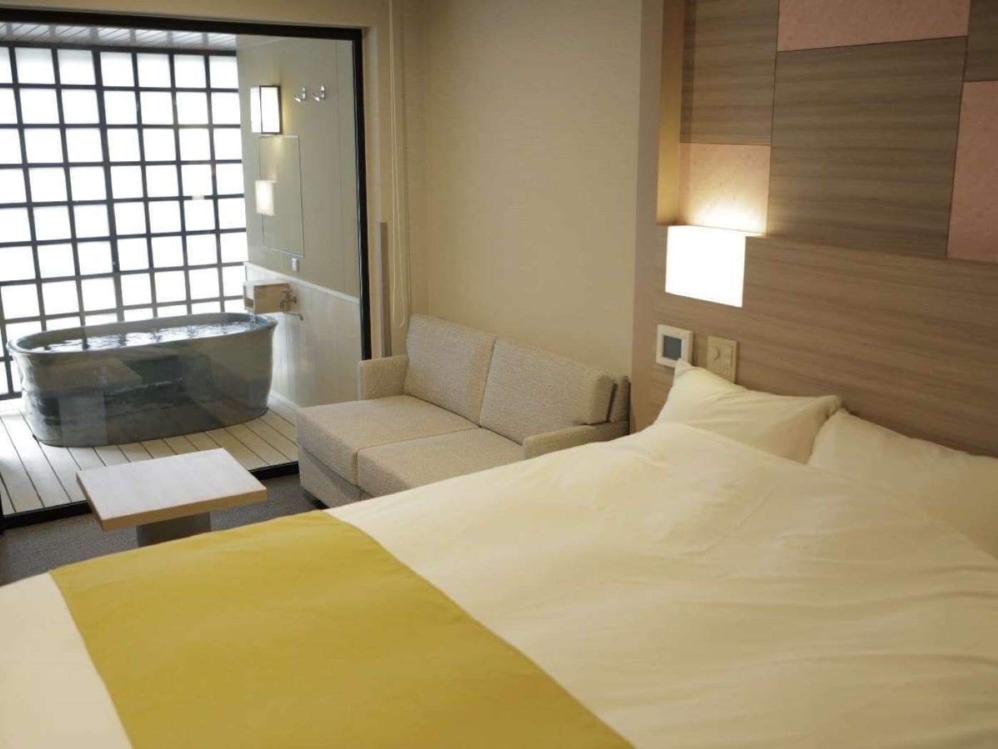 Una habitación de hotel con una cama grande, un sofá, una mesita y un jacuzzi.