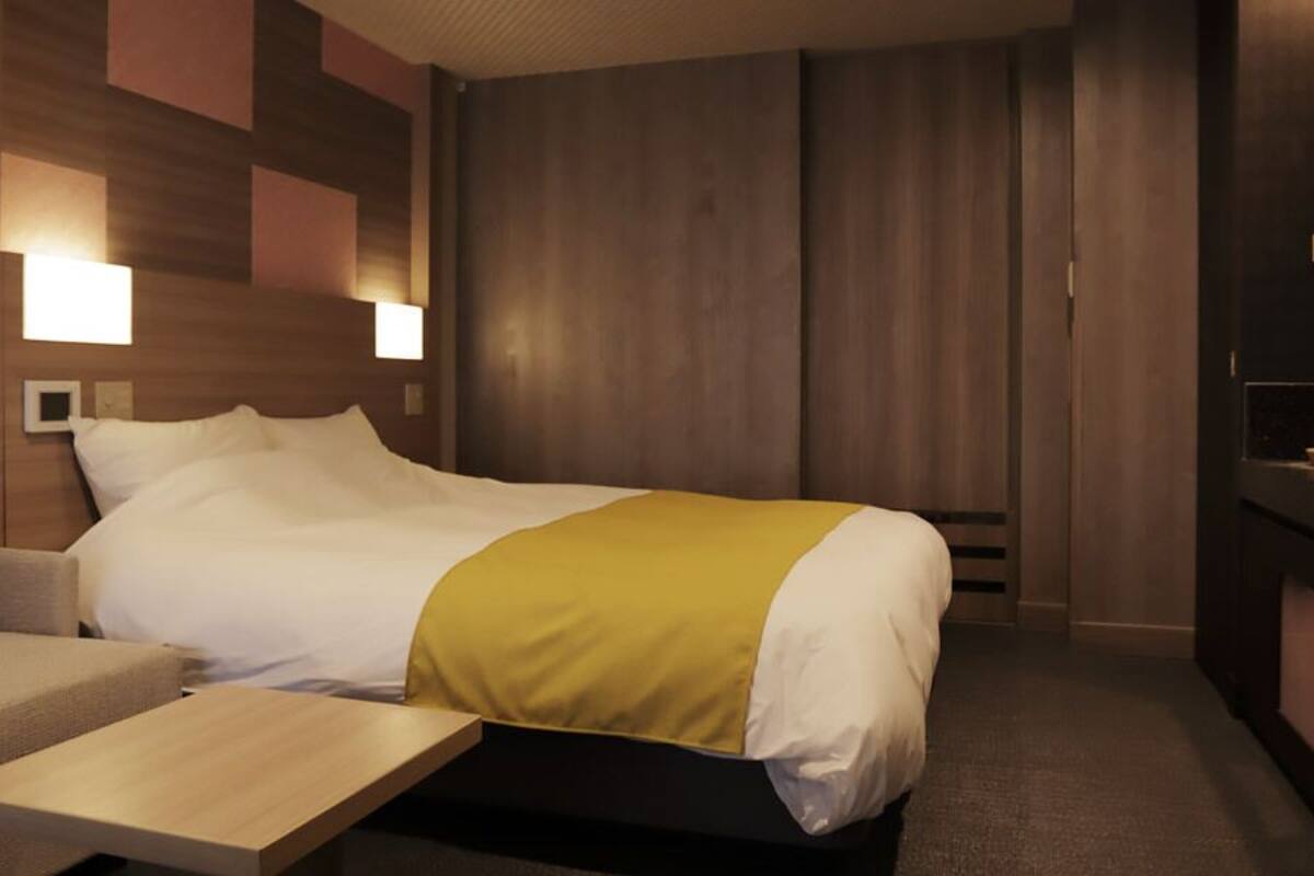 A hotel room with a bed, a sofa, a small table, and a TV.