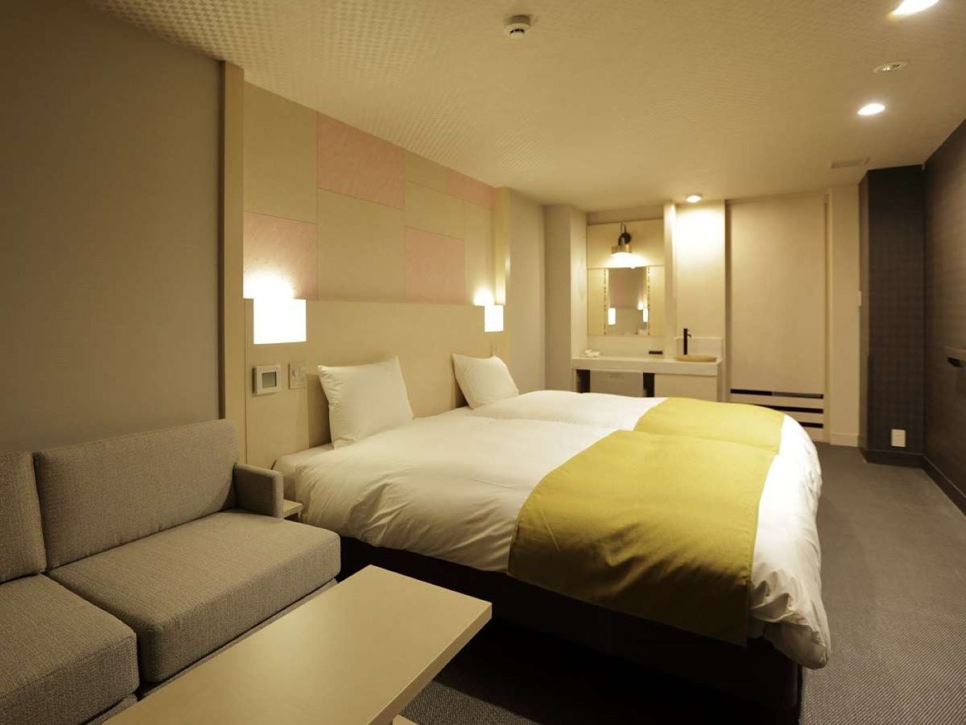 Ett hotellrum med en säng, en soffa, ett sängbord och en spegel.