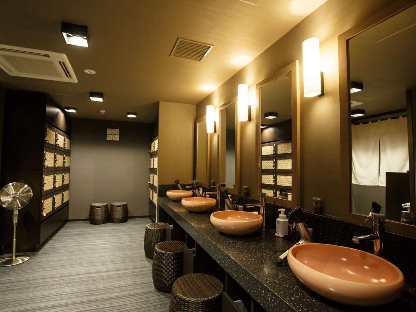 A hotel bathroom with multiple sinks, mirrors, and a fan.