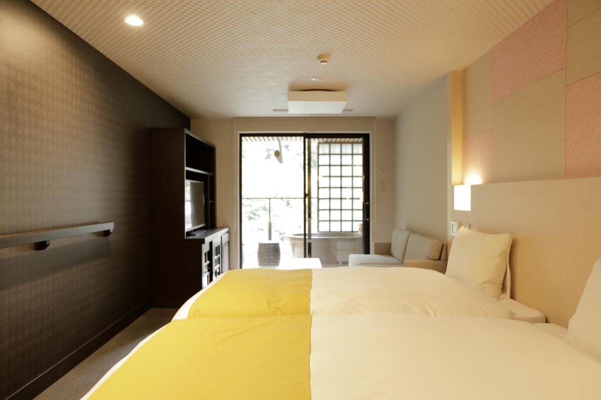 A hotel room with a large bed, a TV, a desk, and a window with a view of the outside.