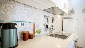 A modern kitchen with a stainless steel sink, a glass shelf, and a patterned backsplash.
