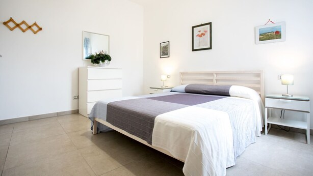 A modern bedroom with a bed, bedside tables, a dresser, and wall art.