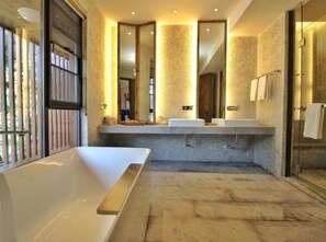 Une salle de bain moderne dotée d’une grande baignoire, de deux lavabos et d’une douche à parois de verre.