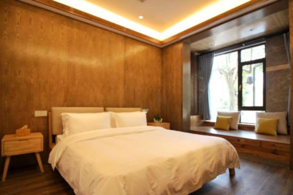 A bedroom with a large bed, wooden walls, a nightstand, and a window with a view.