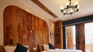 A hotel room with two beds, wooden paneling on the walls, a chandelier, and a large window.