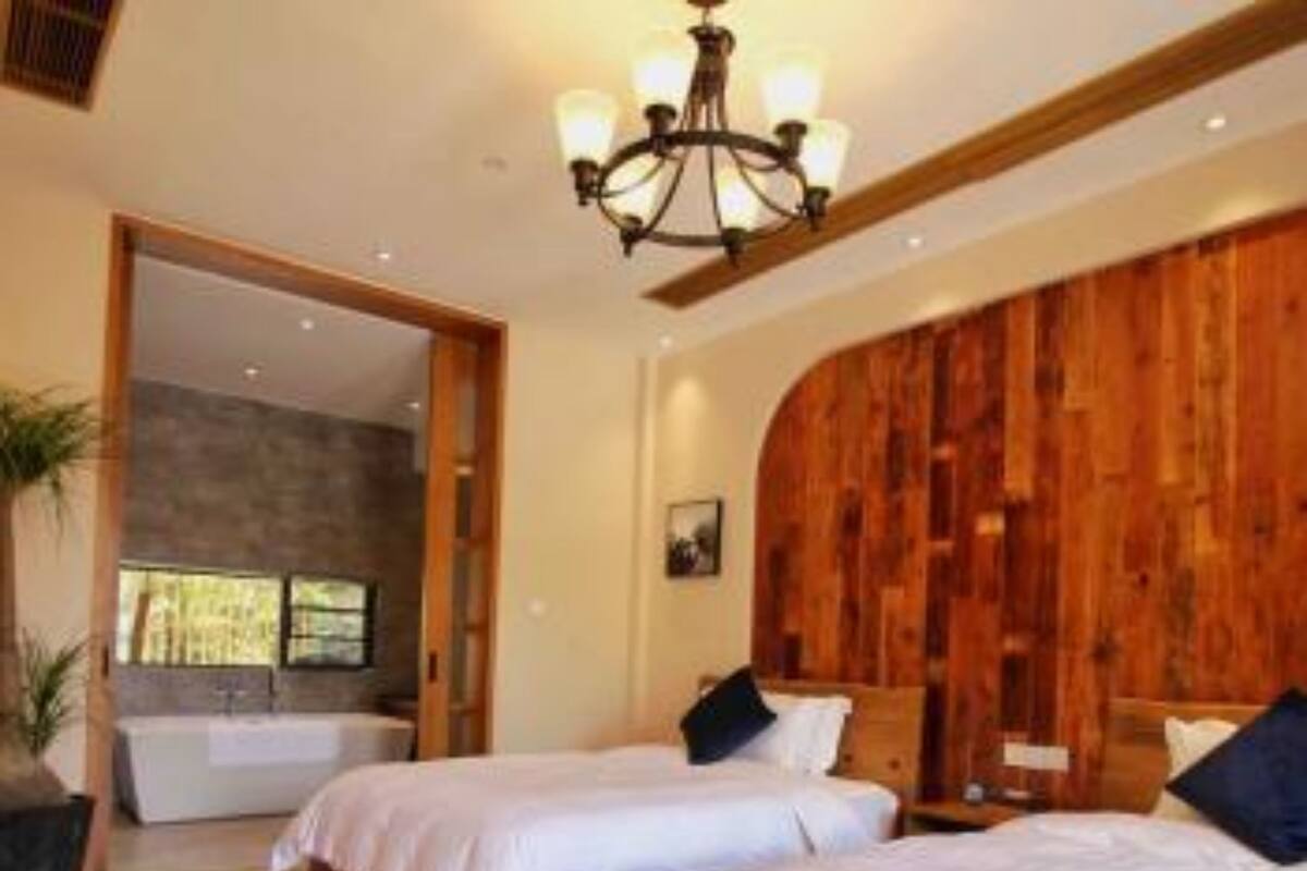 A hotel room with two beds, wooden headboards, a chandelier, and a view of a spa area.