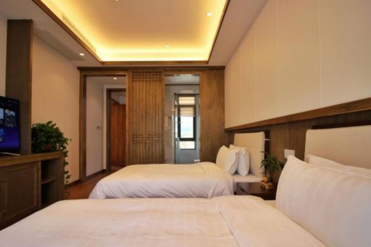 A hotel room with two beds, a television on a wooden stand, and a view of the hallway.