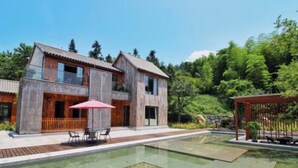 A modern two-story house with a swimming pool, outdoor seating, and a wooden deck.