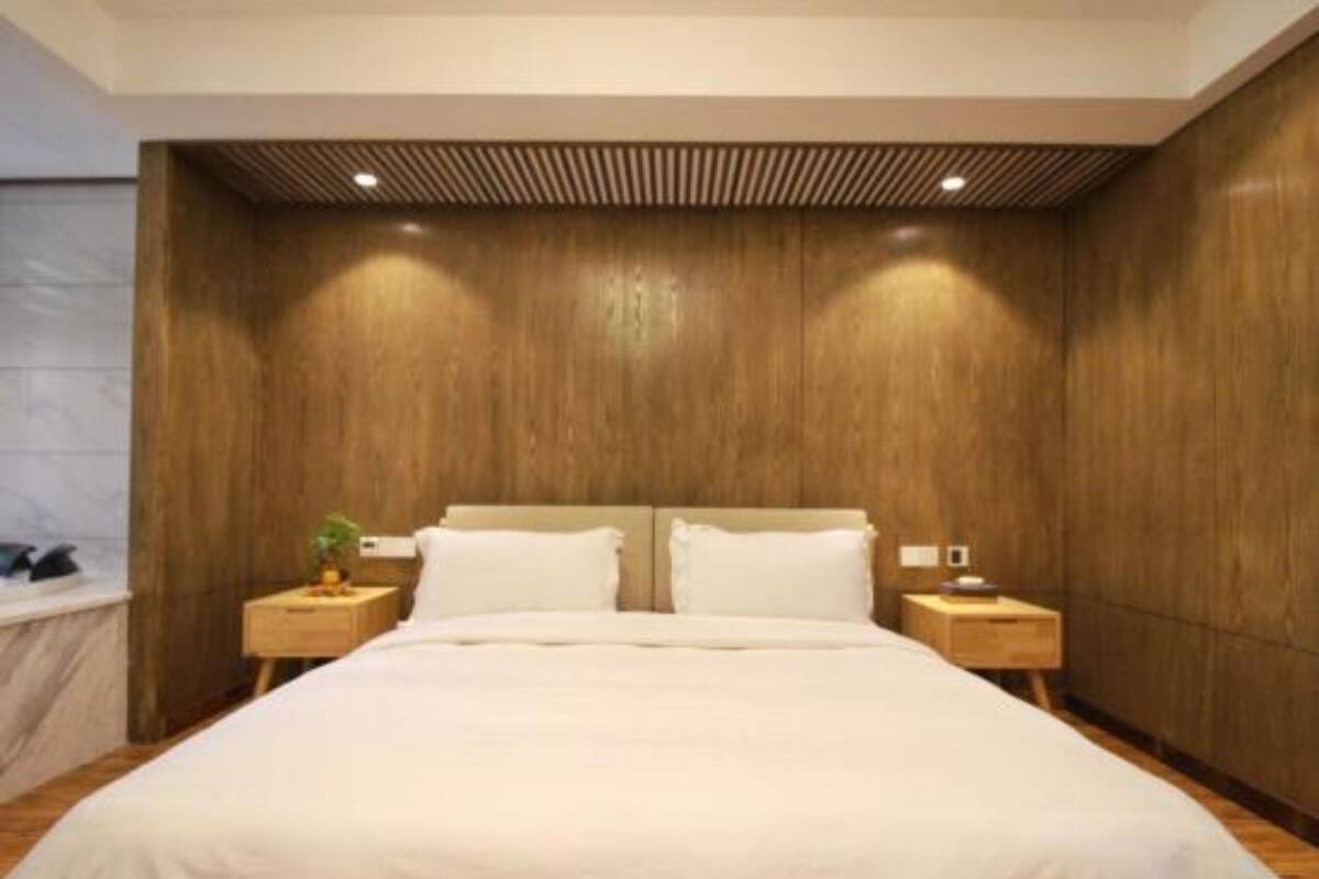 A modern bedroom with a large bed, wooden panel walls, and two bedside tables with lamps.
