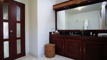 Une salle de bain avec un meuble-lavabo en bois, un miroir, un lavabo et des toilettes.
