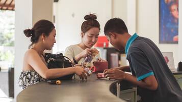 Three people at a counter, possibly in a cafe or restaurant, with a red cup and a smartphone on the table.