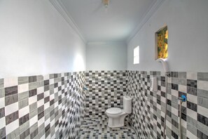 Ein Badezimmer mit Wand in Schachbrettmuster, Toilette und Dusche.