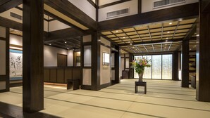 Un interior japonés tradicional con suelo de tatami, vigas de madera y un arreglo floral central.