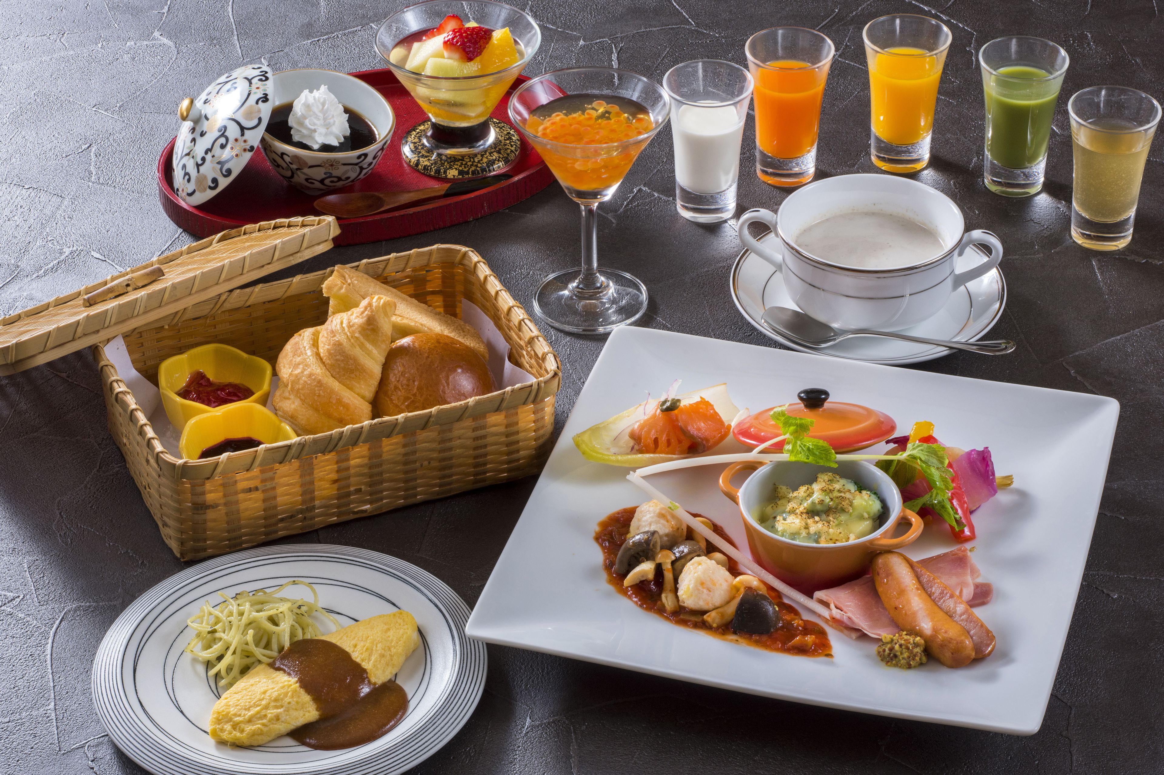 A breakfast setting with a variety of dishes, including bread, eggs, and a salad, along with multiple beverages.