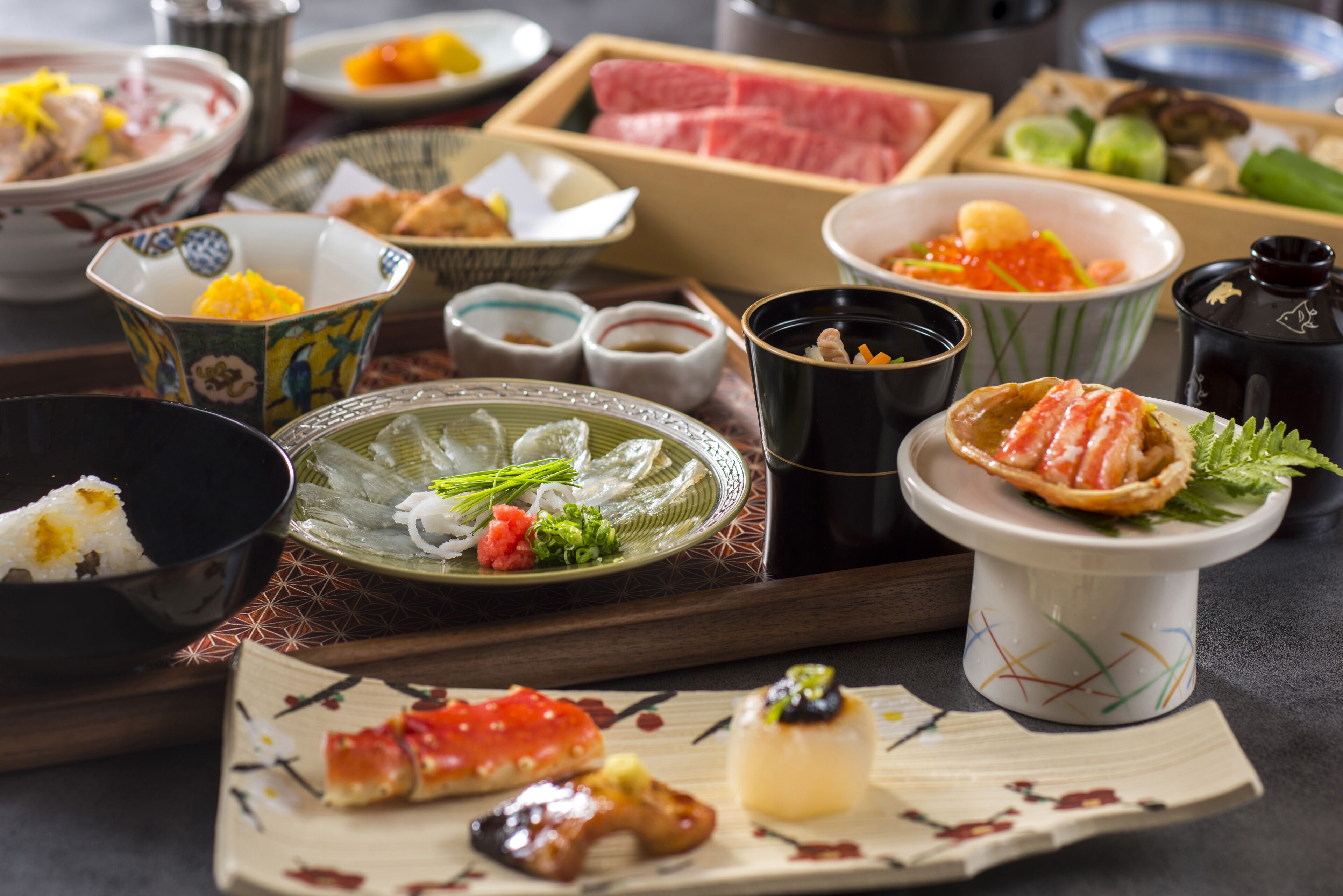 A variety of Japanese dishes including sushi, sashimi, and tempura on a wooden table.