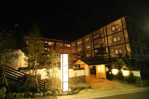 Un edificio tradicional japonés con entrada de piedra, escaleras de madera y un letrero.