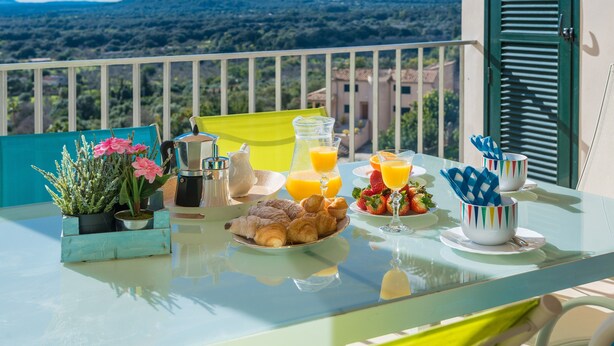 A breakfast table with croissants, strawberries, and orange juice on a balcony with a mountain view. - BIALI - Chalet with terrace in Buger. Free WiFi (Búger)