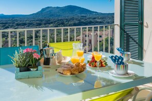 A breakfast table with croissants, strawberries, and orange juice on a balcony with a mountain view. - BIALI - Chalet with terrace in Buger. Free WiFi (Búger)