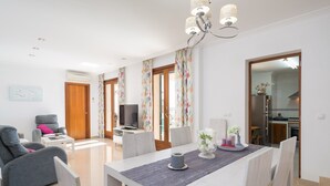 A modern living room with a dining area, a TV, and a kitchen visible through an open door. - BIALI - Chalet with terrace in Buger. Free WiFi (Búger)