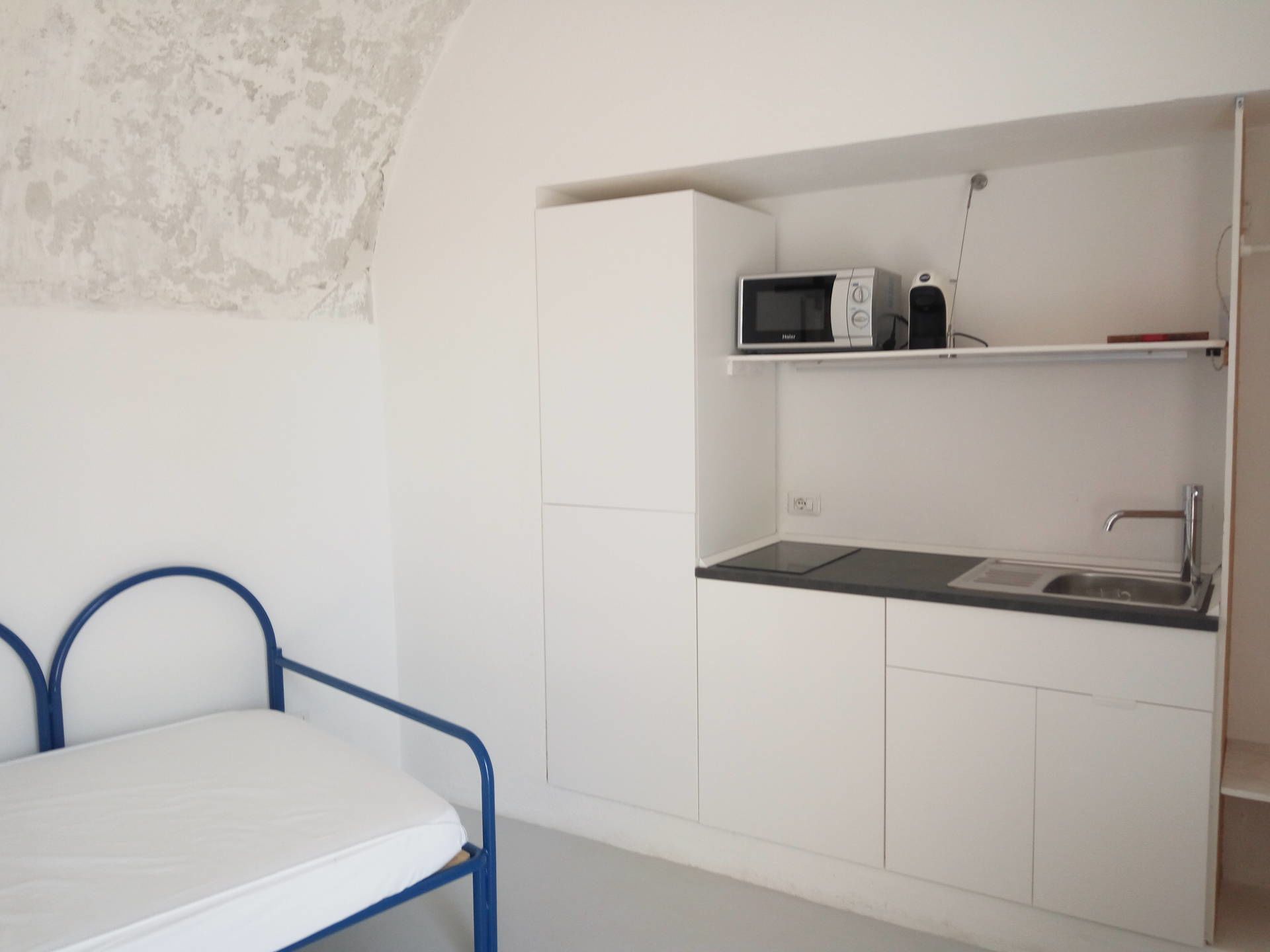 A compact kitchenette with a microwave, sink, and a small shelf.